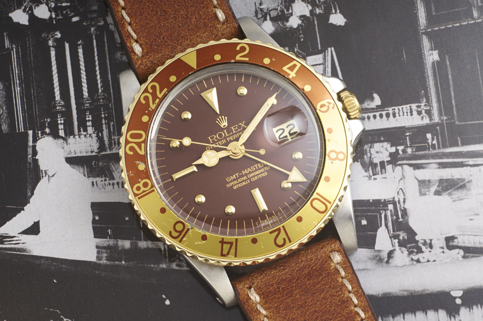 A 1978 Rolex Two-Tone "Root Beer" GMT-Master is shown on a black and white background, featuring a brown and gold finish, leather strap, displaying the time as 4:06 and the date as the 22nd.