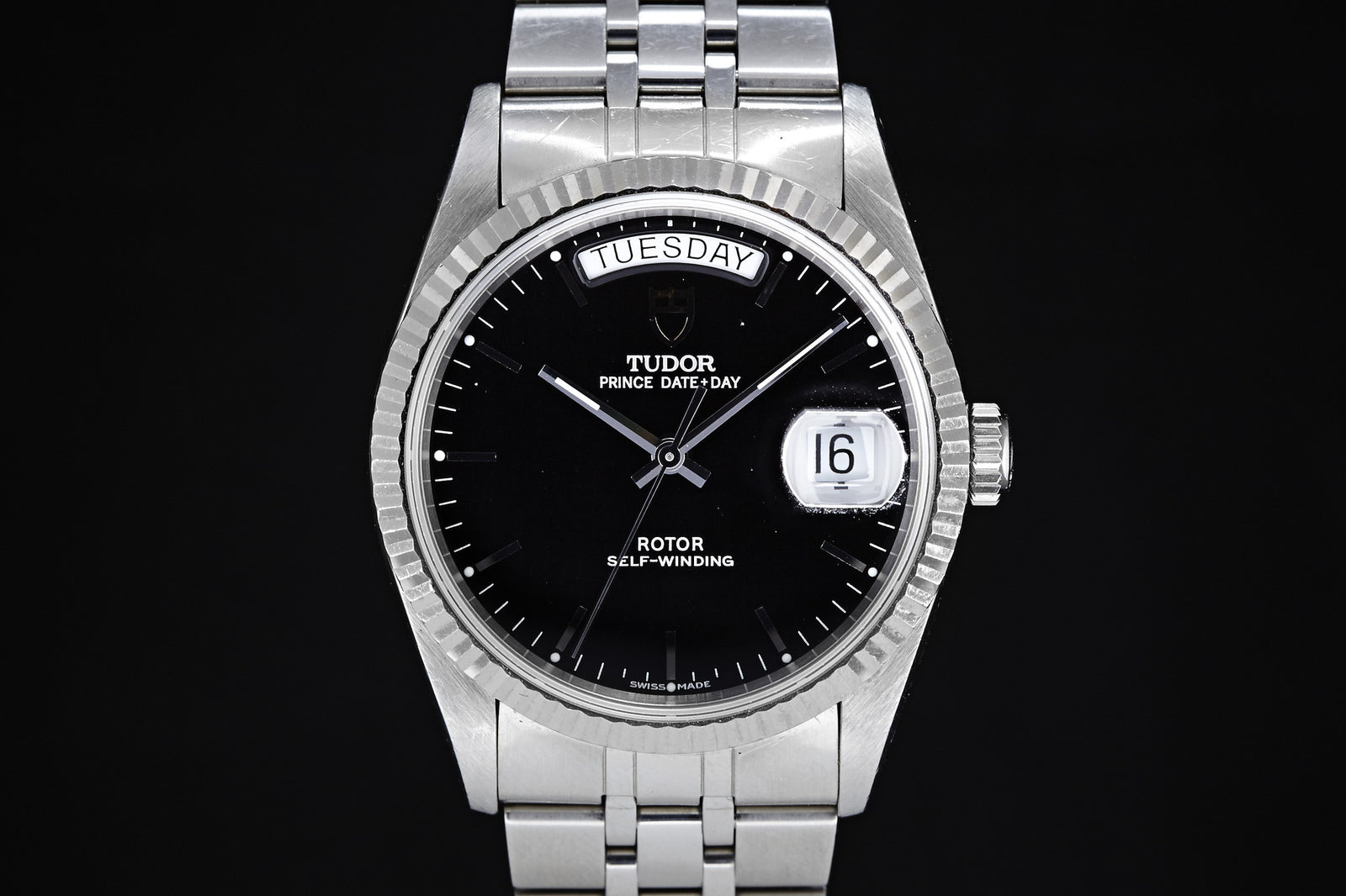 The Tudor Prince Date-Day Black Dial by Tudor features a 36mm steel case, black dial, silver hour markers, date magnifier at the 16th, and "TUESDAY" displayed at the top.